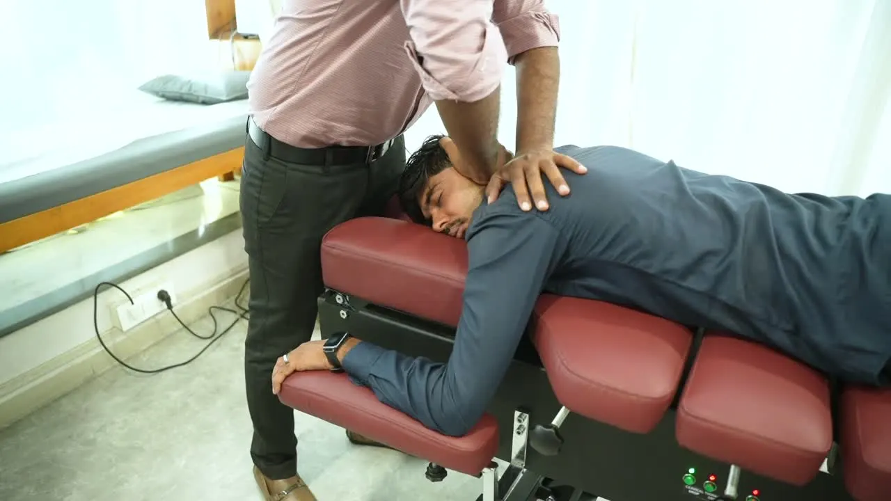 A chiropractor adjusting a patient on the Smart Medicure air drop table, and the electric treatment table rising on its scissor lift